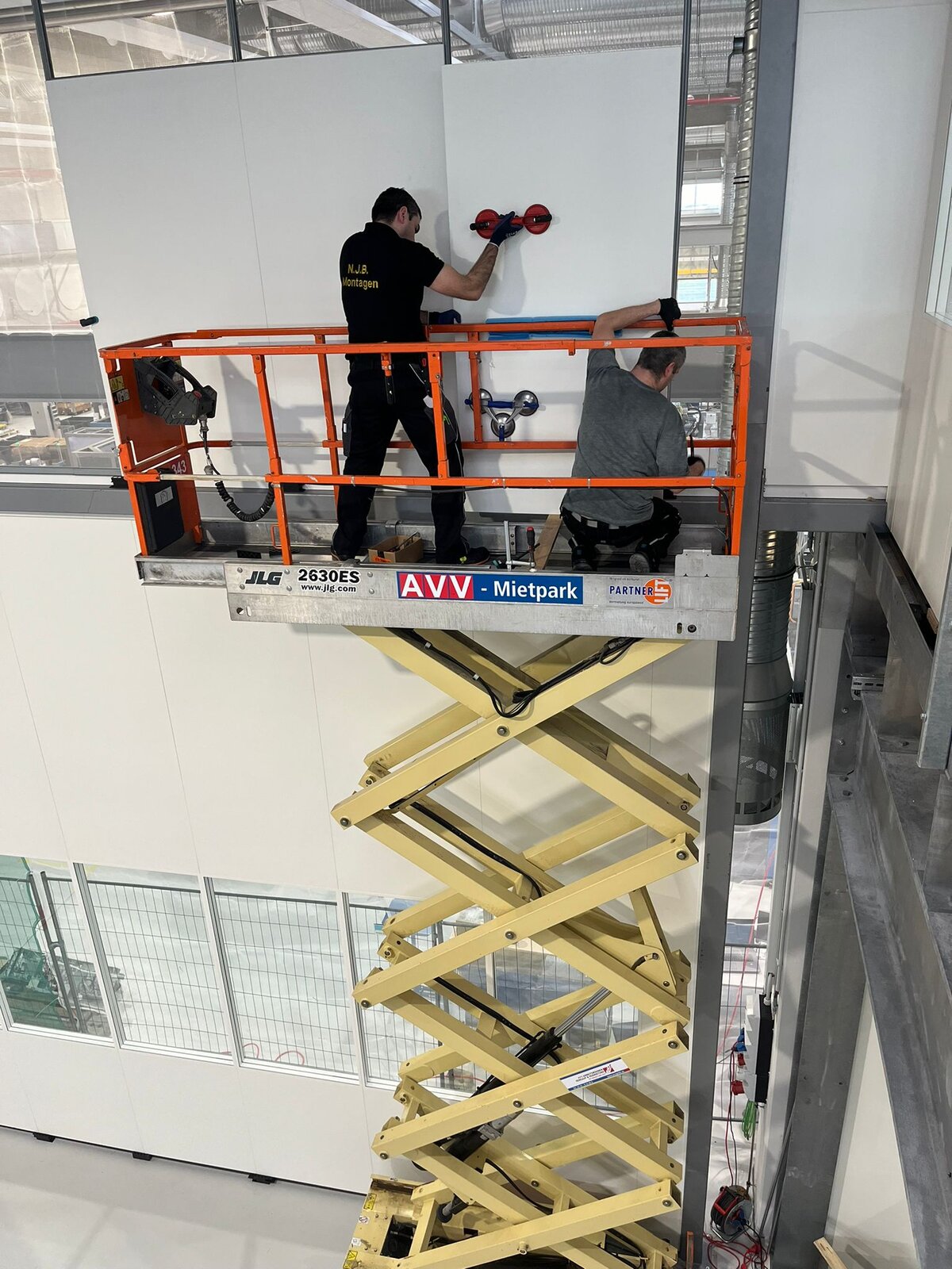 NJB Montagen Team bei der Wandmontage auf einer Hebebühne